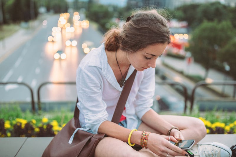 A person sits outside looking down at their phone. It's OK to text someone that you don't actually w...