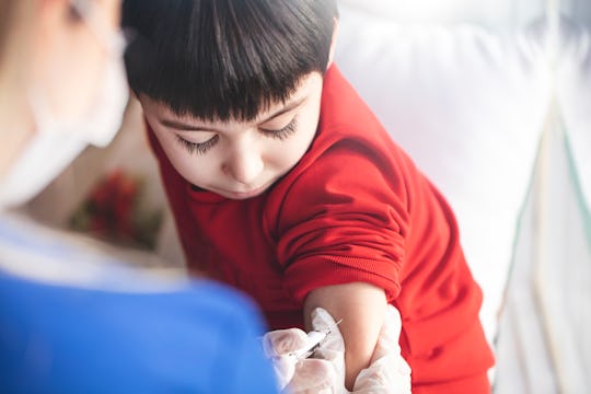 This picture depicts a young female clinician using a syringe to inject a concept COVD-19 liquid vac...