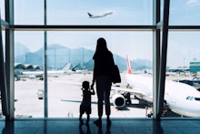 Silhouette of joyful young Asian mother holding hands with cute little daughter looking at airplane ...