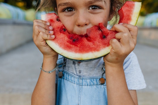 Little boy eating a piece of watermelon outdoors