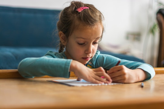 Little girl coloring with crayon in the living room