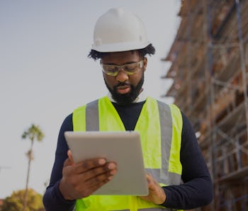 A young black man is a project manager at a residential construction site.