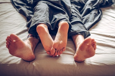 Adult couple's feet looking out of bed