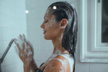 Woman enjoying the shower in the bathroom at home. She is washing her hair.