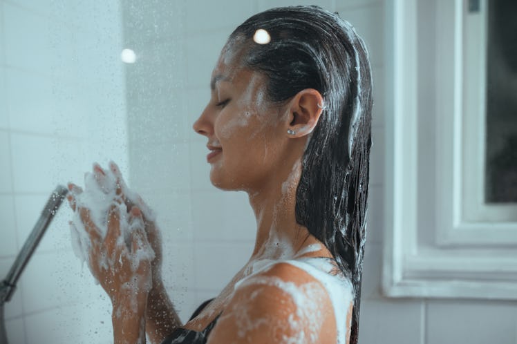 Woman enjoying the shower in the bathroom at home. She is washing her hair.