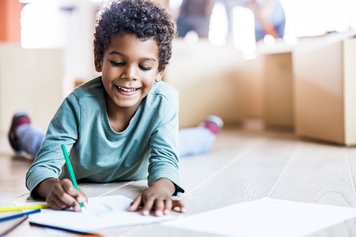 Small boy smiling while drawing on the floor