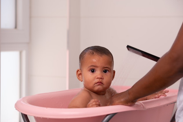 A cute baby is bathing in the tub.