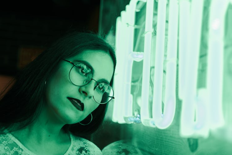 Young woman staring at neon green lights on Friday the 13th 2021.