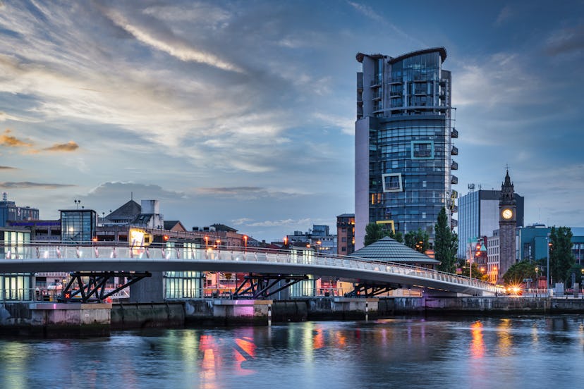 Belfast City Sunset with colorful twilight over Lagan Weir Pedestrian and Cycle Bridge spanning over...