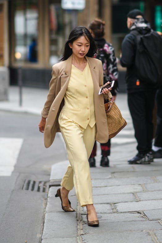 PARIS, FRANCE - JUNE 23: A guest wears a beige oversized blazer jacket, a pale pastel yellow double ...