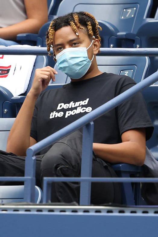 Cordae wears a "defund the police" shirt while watching as Naomi Osaka at the 2020 US Open.