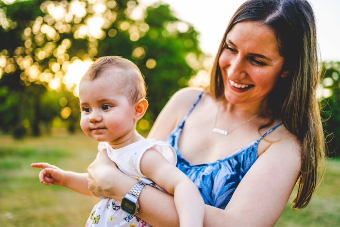 Smiling mother holding her little baby girl in the park