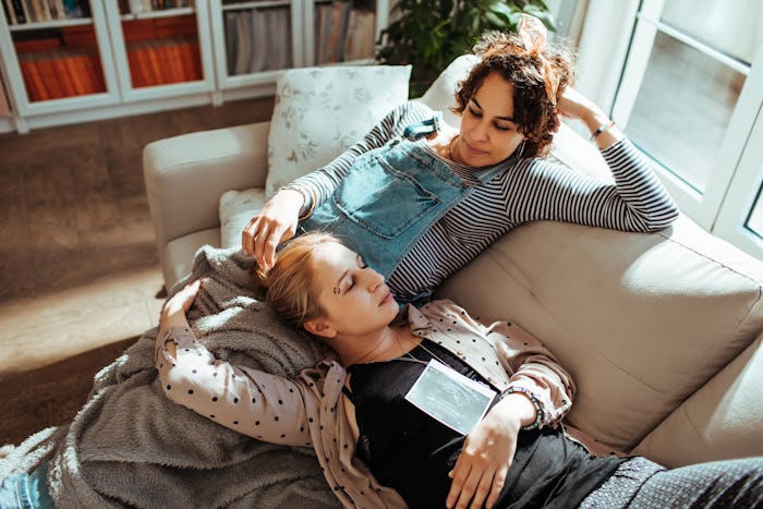 Close up of a female couple looking at the ultrasound photo of their baby while cuddling on a sofa