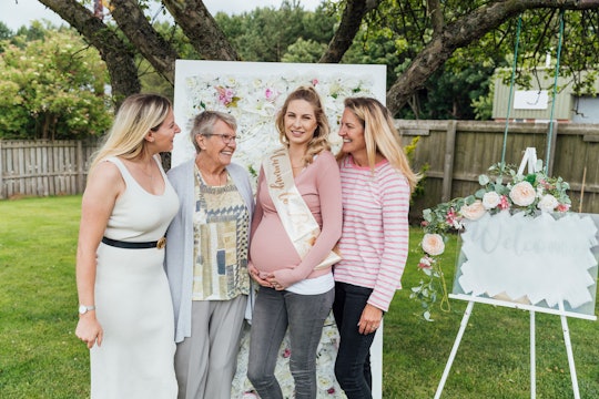 A shot of three women smiling at a mother to be at her outdoor baby shower.