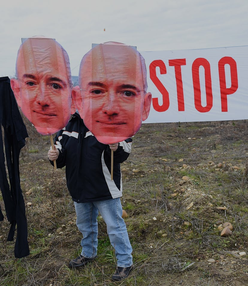 An activist of the Attac association holds a cutout sign depicting Amazon CEO Jeff Bezos, in front o...