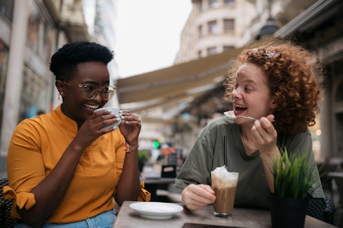 Two friends laughing while drinking coffee together after reconnecting. Experts explain how to recon...