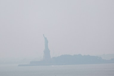 NEW YORK, NEW YORK - JULY 20: The Statue of Liberty sits behind a cloud of haze on July 20, 2021 in ...