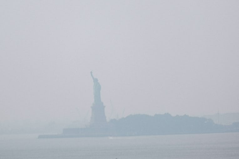 NEW YORK, NEW YORK - JULY 20: The Statue of Liberty sits behind a cloud of haze on July 20, 2021 in ...