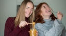 2 friends smiling and tasting their honey jelly recipe from TikTok.