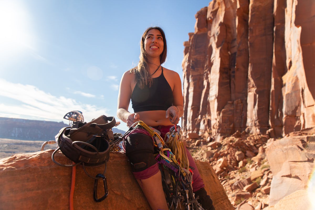 Young woman about to climb mountain, showing she'd be a sport climber if she competed in the Olympics, per her zodiac sign.
