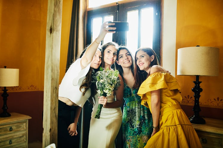 Friends take a selfie at their coworker's wedding to post on Instagram with some wedding captions fo...