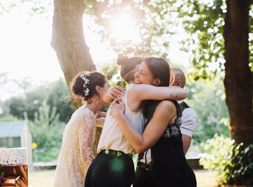 Young woman attending her coworker's wedding, hugging bride.