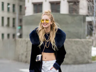 Chiara Ferragni wearing white pants, cropped top, sneaker, black coat with fur collar outside Michae...