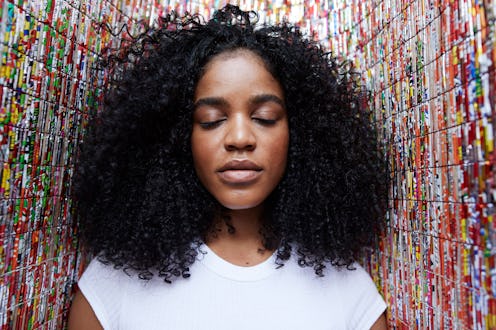 Close-up of young female with eyes closed standing against patterned wall