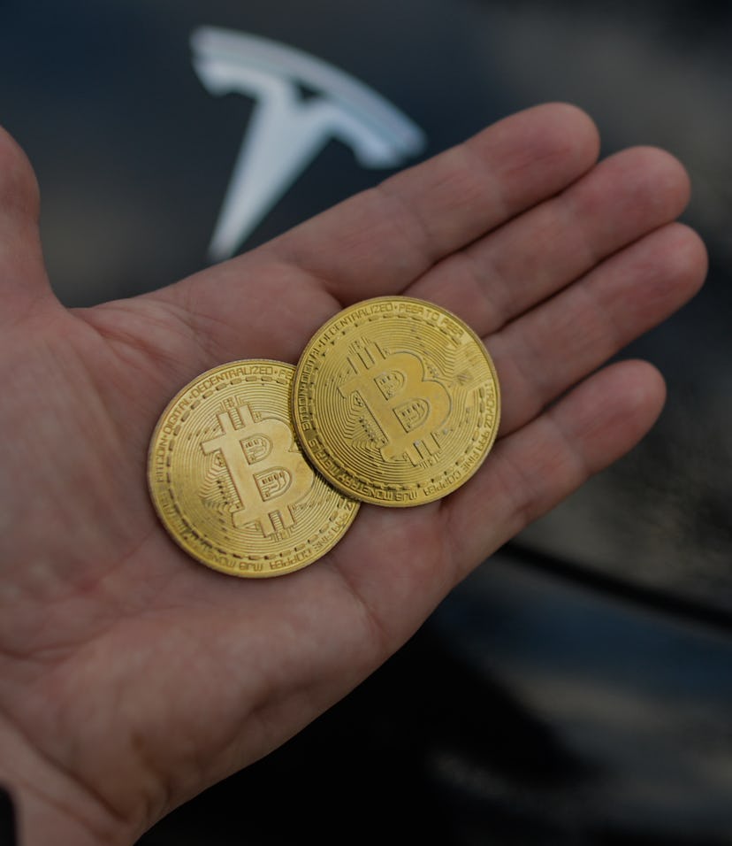 Illustrative image of two commemorative bitcoins seen in front of the Tesla car logo.
On Saturday, F...