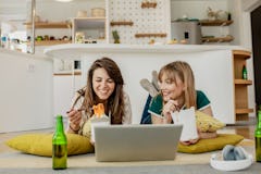 A young couple orders takeout food for a cozy night in, and eats it while watching a show on a lapto...