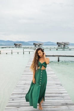 Woman wearing a green wedding guest beach dress. 