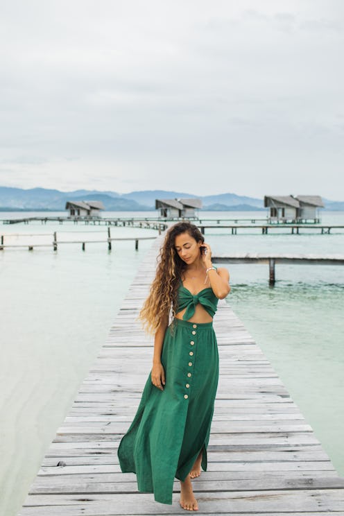 Woman wearing a green wedding guest beach dress.
