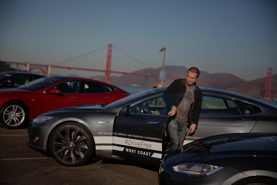 Daniel Myggen, Tesla sales operations, gets out of a Tesla Model S after parking it during a stop in...