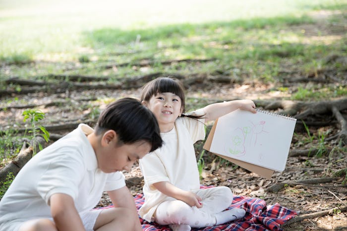 kids coloring outside, a girl and a boy