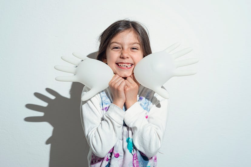 Little girl playing with surgeon gloves inflated like a balloon.
