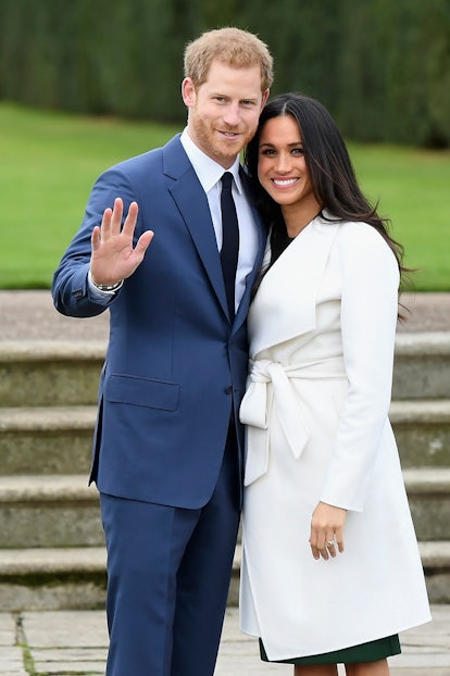Markle is shown here with Prince Harry. She wears a white coat and is smiling. 