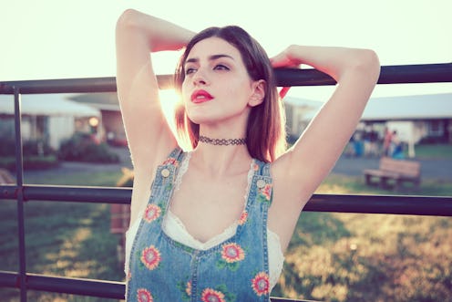 90s woman wearing overalls and choker necklace. Beautiful woman wearing red lipstick. Her underarms,...