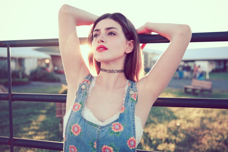 90s woman wearing overalls and choker necklace. Beautiful woman wearing red lipstick. Her underarms,...