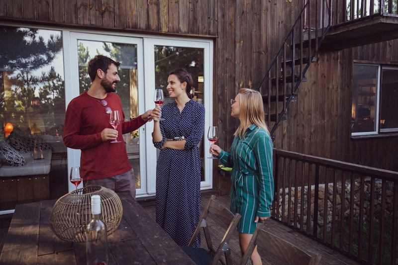 Depicting three people in casual wear enjoying a good laugh and the surroundings over a glass of win...