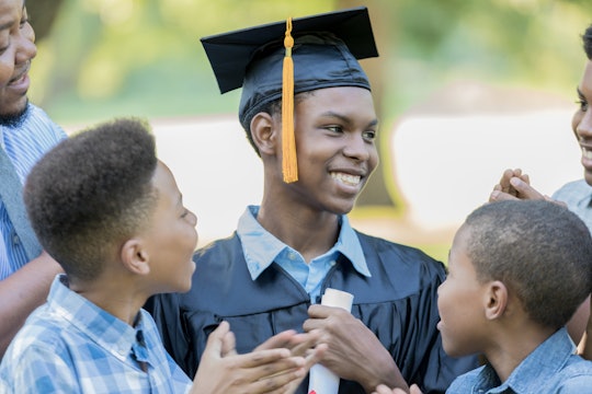 Proud African American boy is surrounded by his parents and brothers after graduating from high scho...