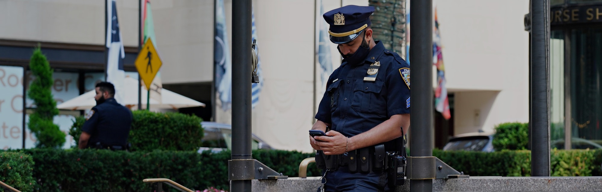 NEW YORK, NEW YORK - AUGUST 01:  An NYPD officer wearing a protective mask looks at his phone at Roc...