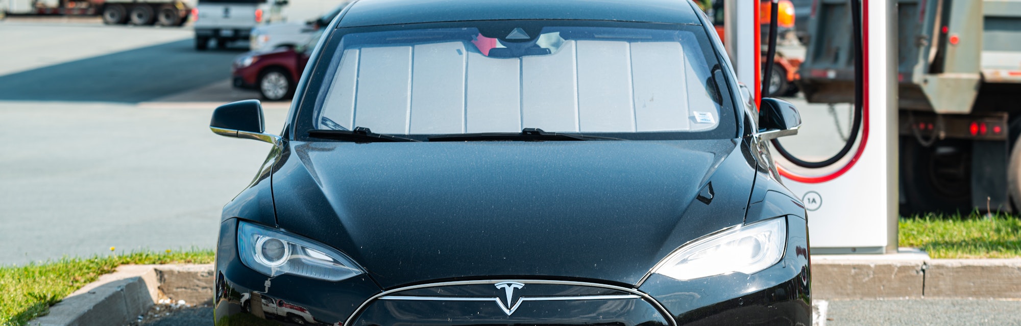 Enfield, Canada - June 7, 2021 - A Tesla Model S sedan at a Supercharger charging terminal at a gas ...
