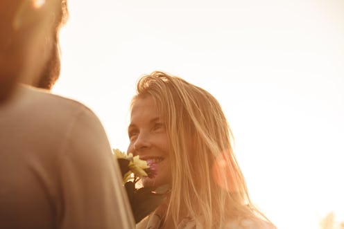 Rear-lit shot during sunset of a happy woman looking at a man whose face is not visible
