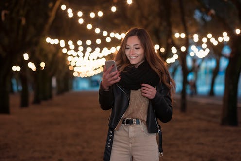 Young woman using her smartphone at park during Christmas time.