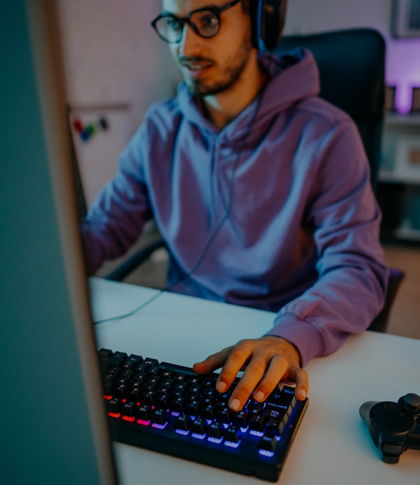Young man playing online video games at home on PC