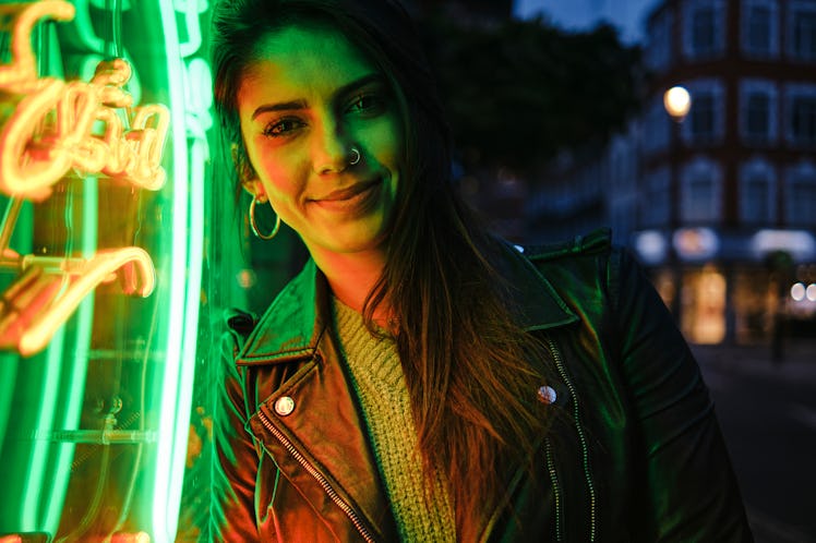Young woman in green neon lights, preparing for new moon in Leo.