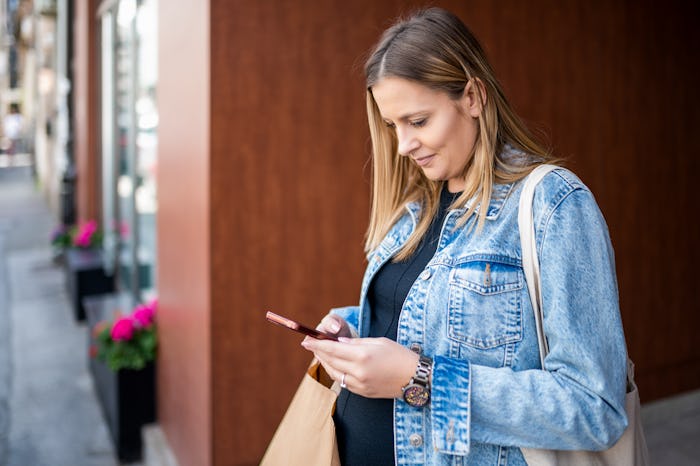 Pregnant woman standing and using mobile phone