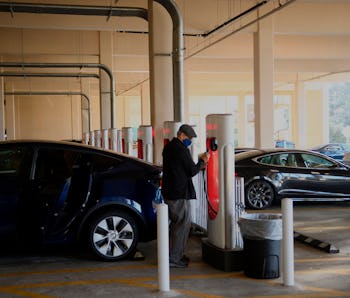 Tesla Inc. electric vehicles charge at the company's supercharger station inside a parking garage on...