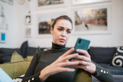 Attractive Caucasian woman using a smart phone at home, looking sad and distressed