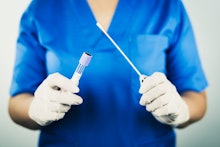 Nurse holds a test tube for taking patient specimen sample. COVID-19 swab collection kit, test tube ...